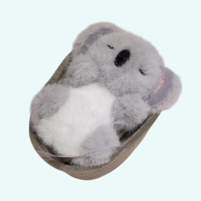 Grey koala cuddly plush lying in a cute little cradle sleeping on a plain background