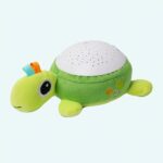 Green turtle plush with a blue and red crest and a white speaker on his back
