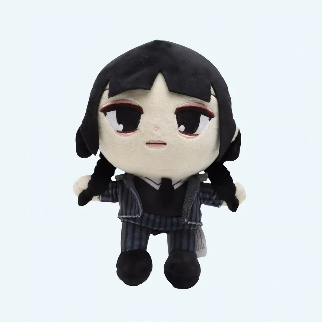 Img_1000X1000_Duo_Peluches_Originales_Serie_Mercredi13-Photoroom.jpeg Plush toy representing Wednesday Addams, character from the Netflix series. She wears a black striped outfit, has black hair in two braids, and a serious expression. The plush is standing against a blue background.